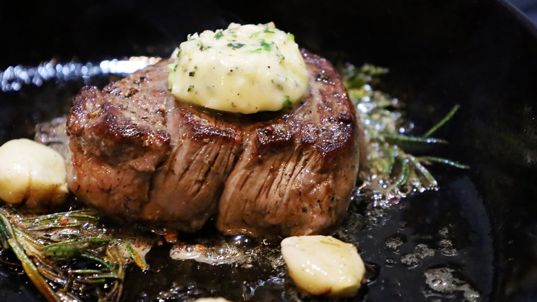 filet mignon with garlic and herbs in cast iron skillet