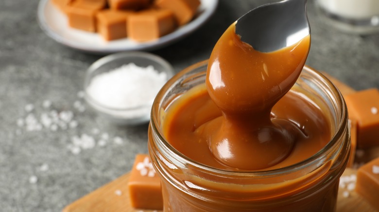 Jar of caramel sauce with unwrapped caramels in background