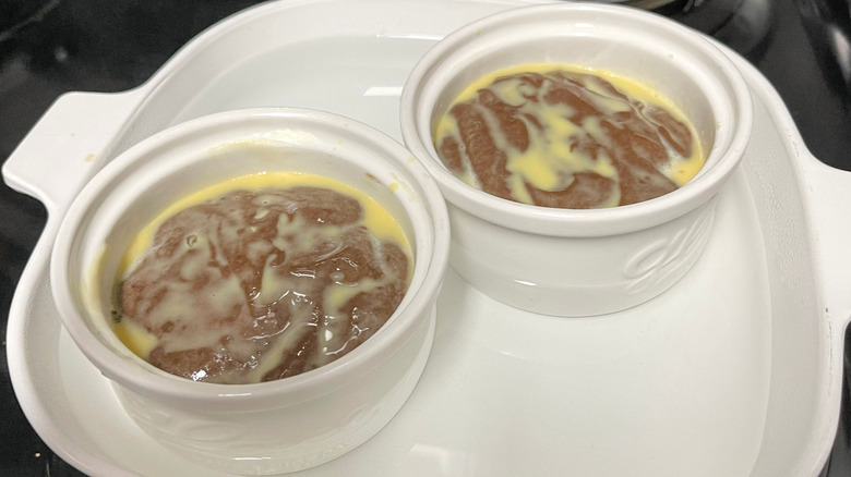 Unbaked chocoflans in ramekins inside of water bath