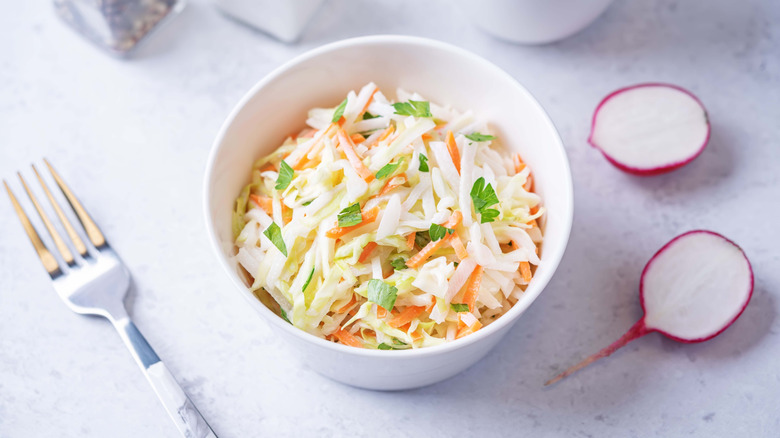 coleslaw in a bowl with fork and radishes on the side