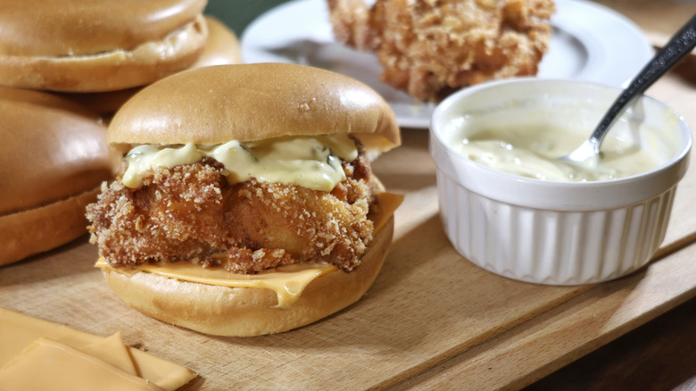 copycat filet-o-fish sandwich on cutting board next to ramekin of tartar sauce